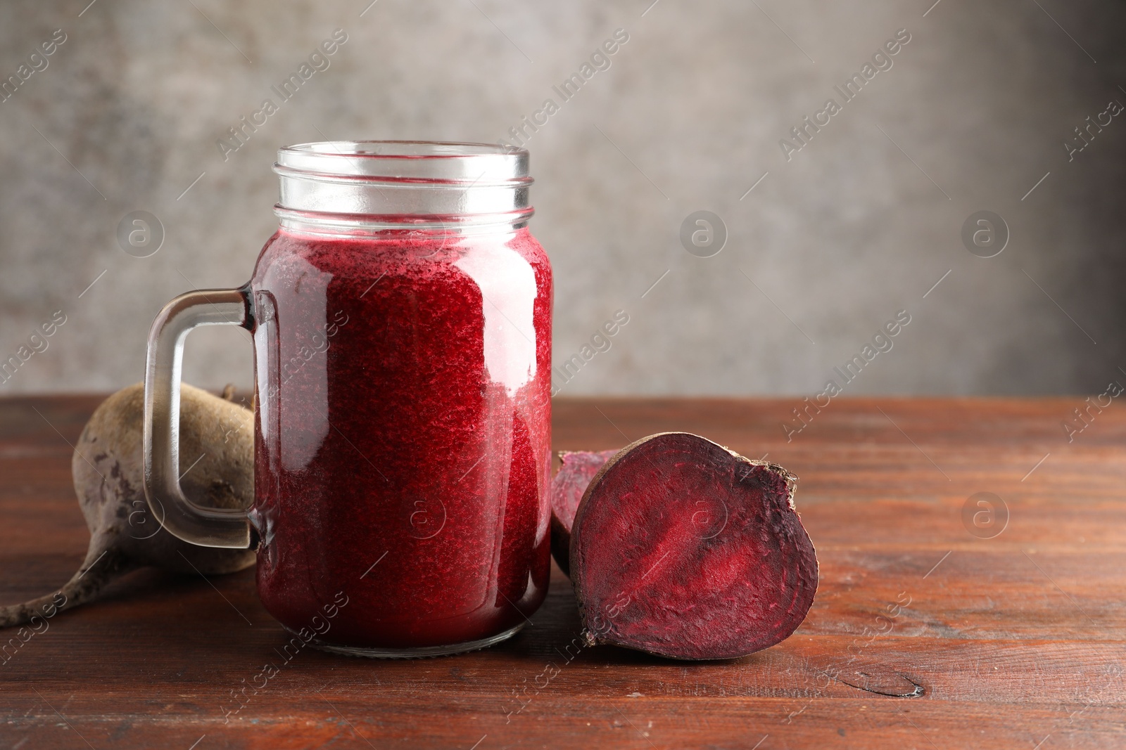 Photo of Fresh beetroot smoothie in mason jar and vegetables on wooden table, closeup. Space for text