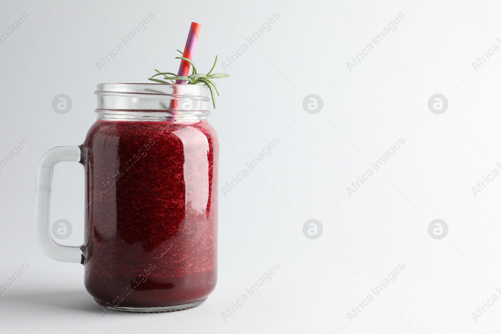 Photo of Fresh beetroot smoothie in mason jar on light background, closeup. Space for text