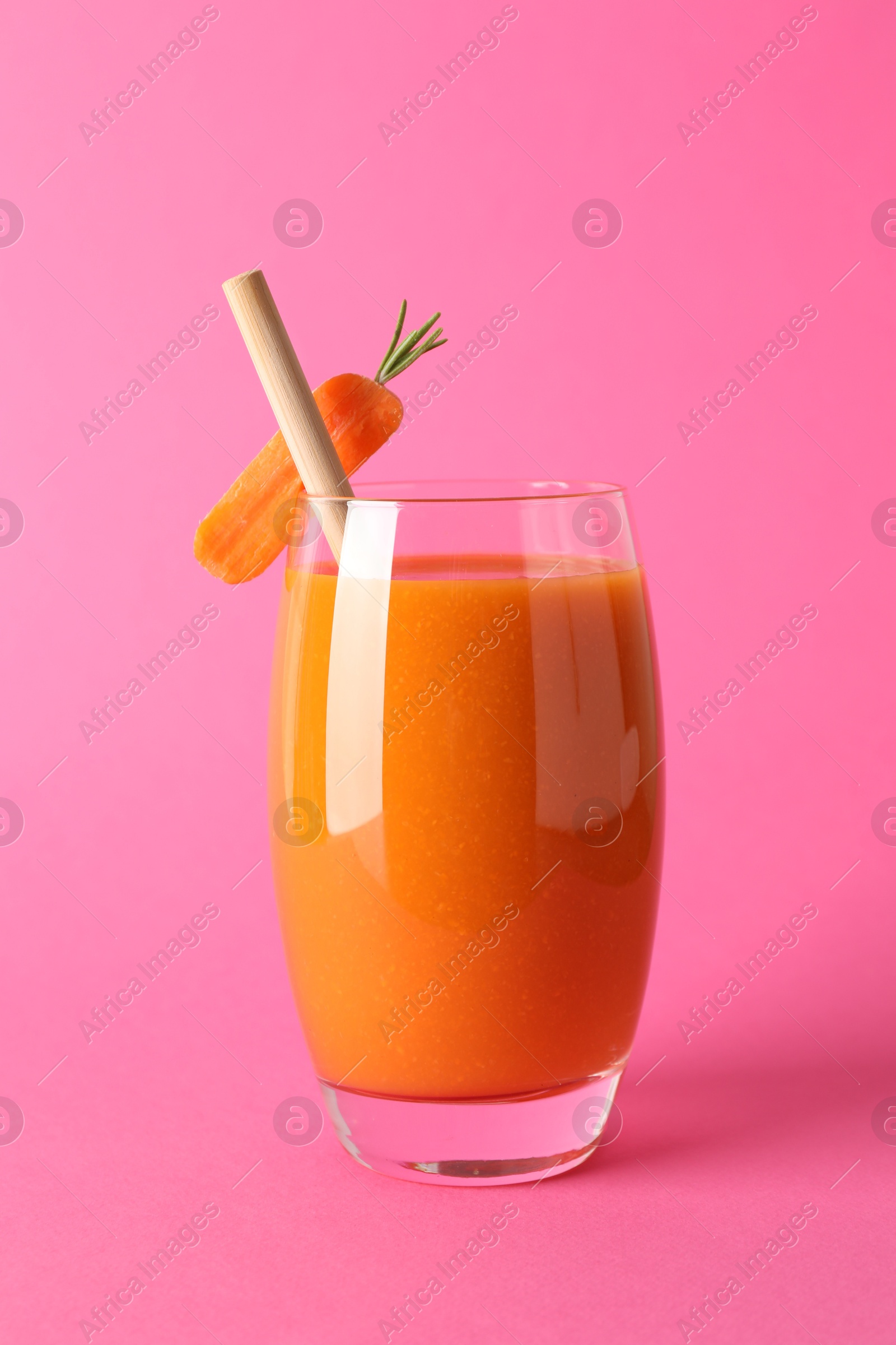 Photo of Fresh carrot smoothie in glass on pink background, closeup