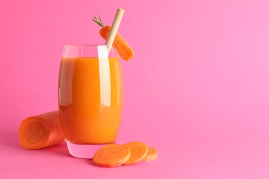 Photo of Fresh carrot smoothie in glass and cut vegetable on pink background, closeup. Space for text