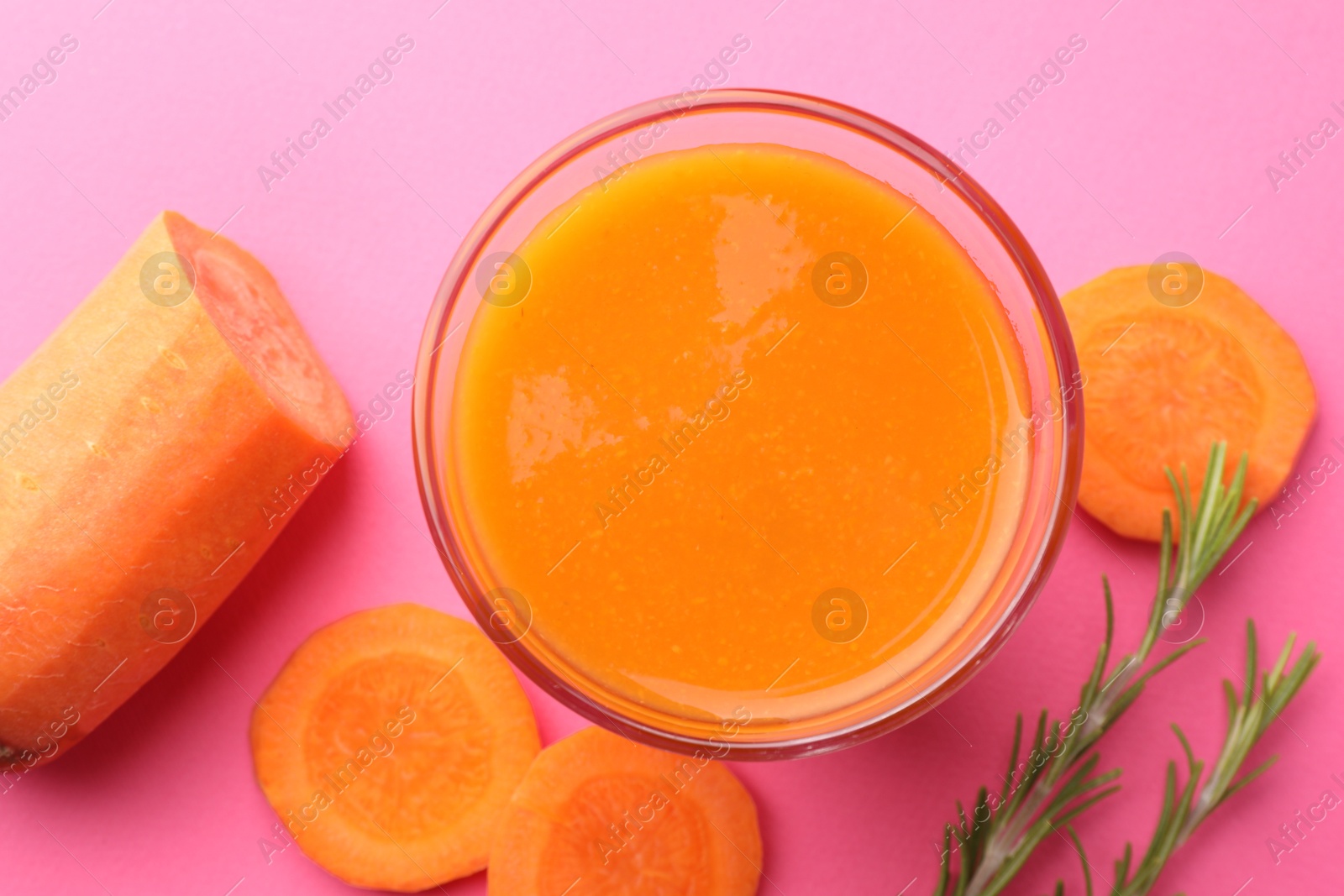 Photo of Fresh carrot smoothie in glass, rosemary and cut vegetable on pink background, flat lay