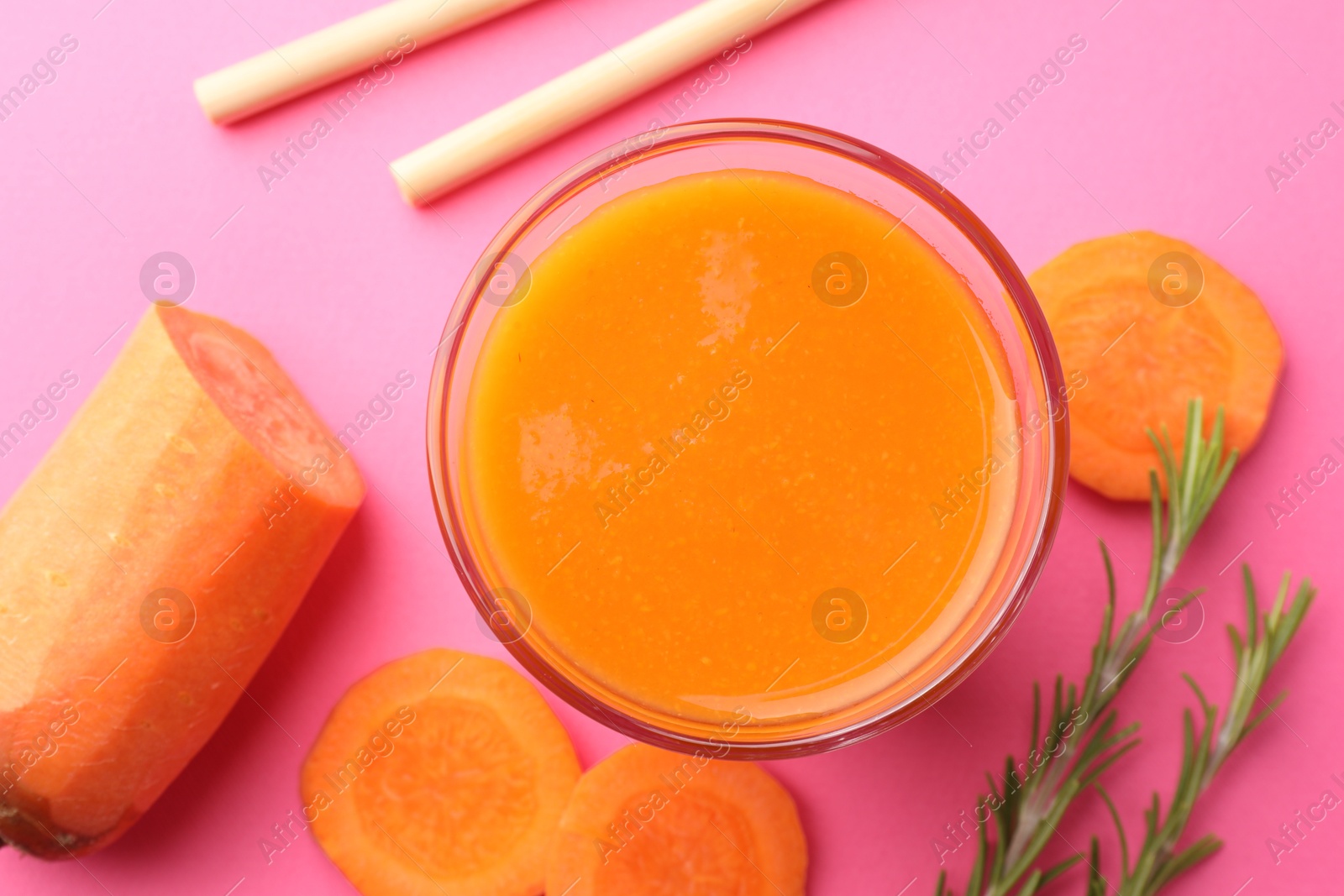 Photo of Fresh carrot smoothie in glass, rosemary and cut vegetable on pink background, flat lay