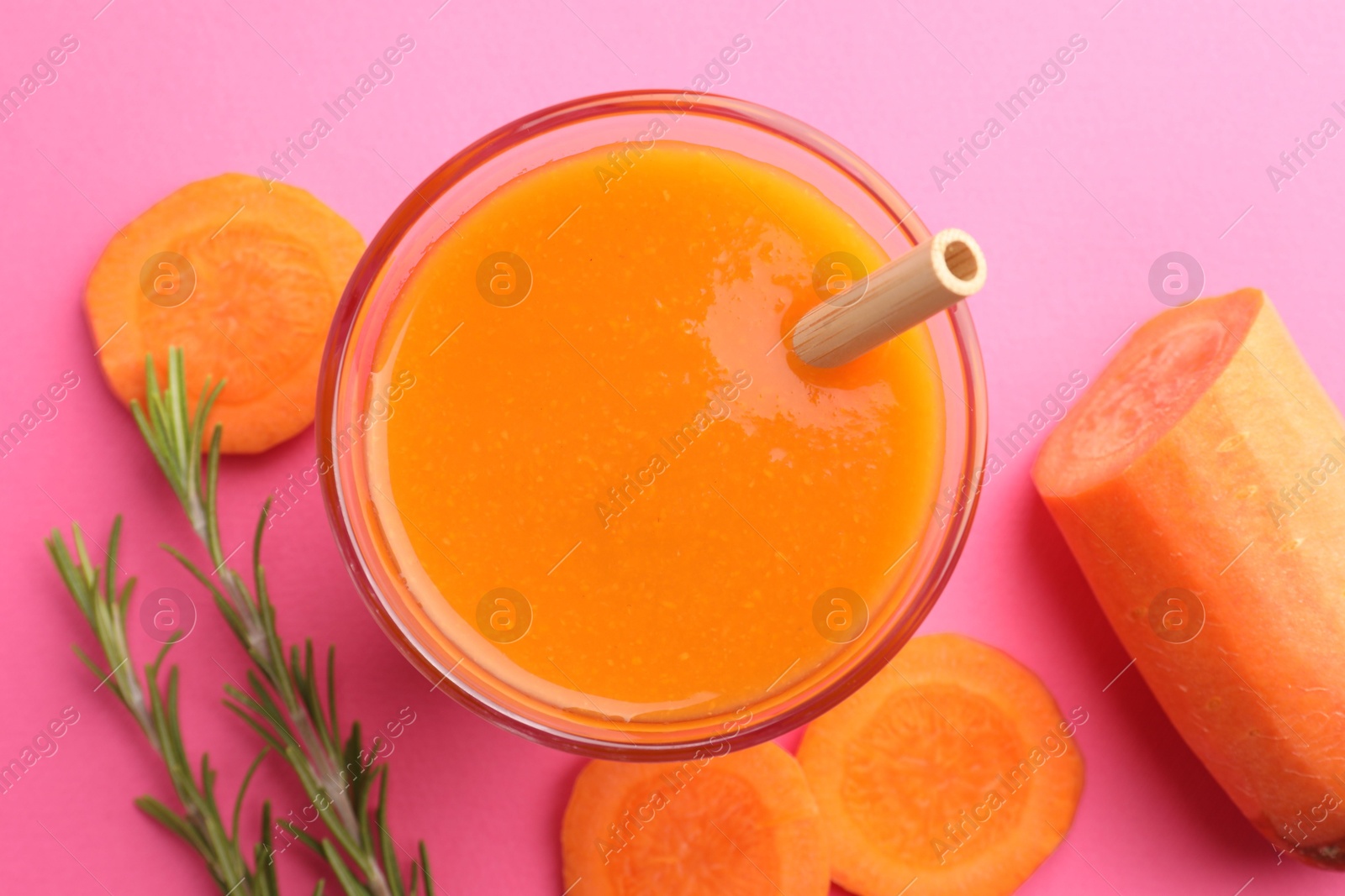 Photo of Fresh carrot smoothie in glass, rosemary and cut vegetable on pink background, flat lay