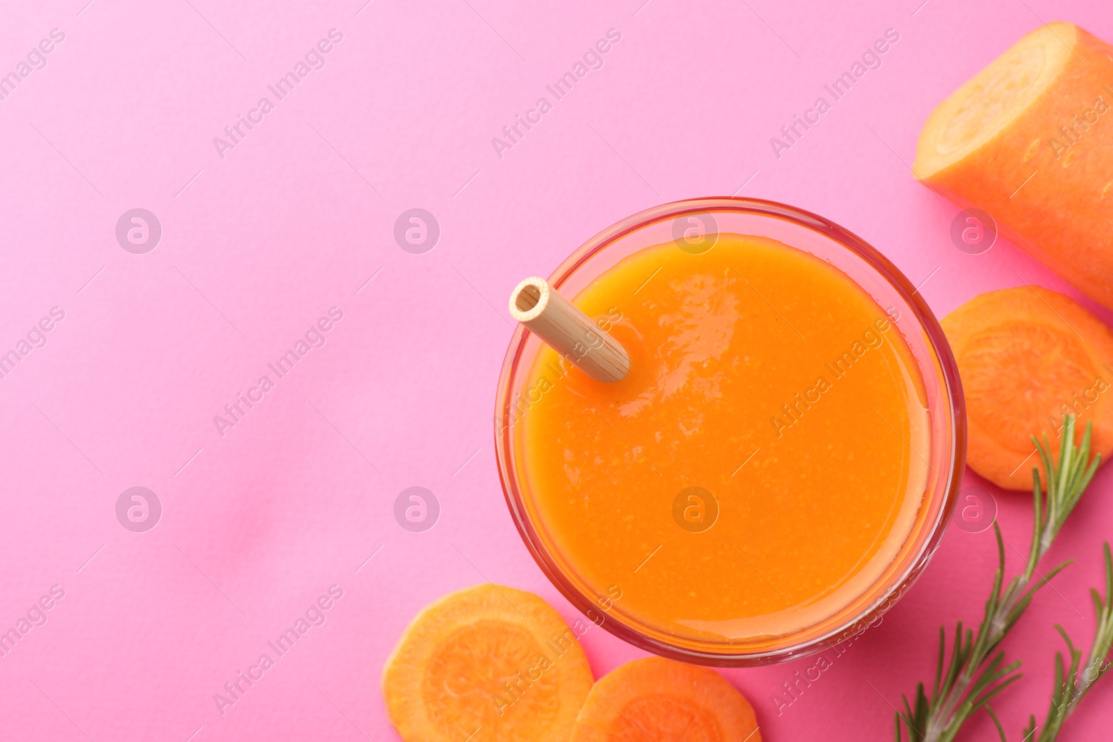 Photo of Fresh carrot smoothie in glass, rosemary and cut vegetable on pink background, flat lay. Space for text