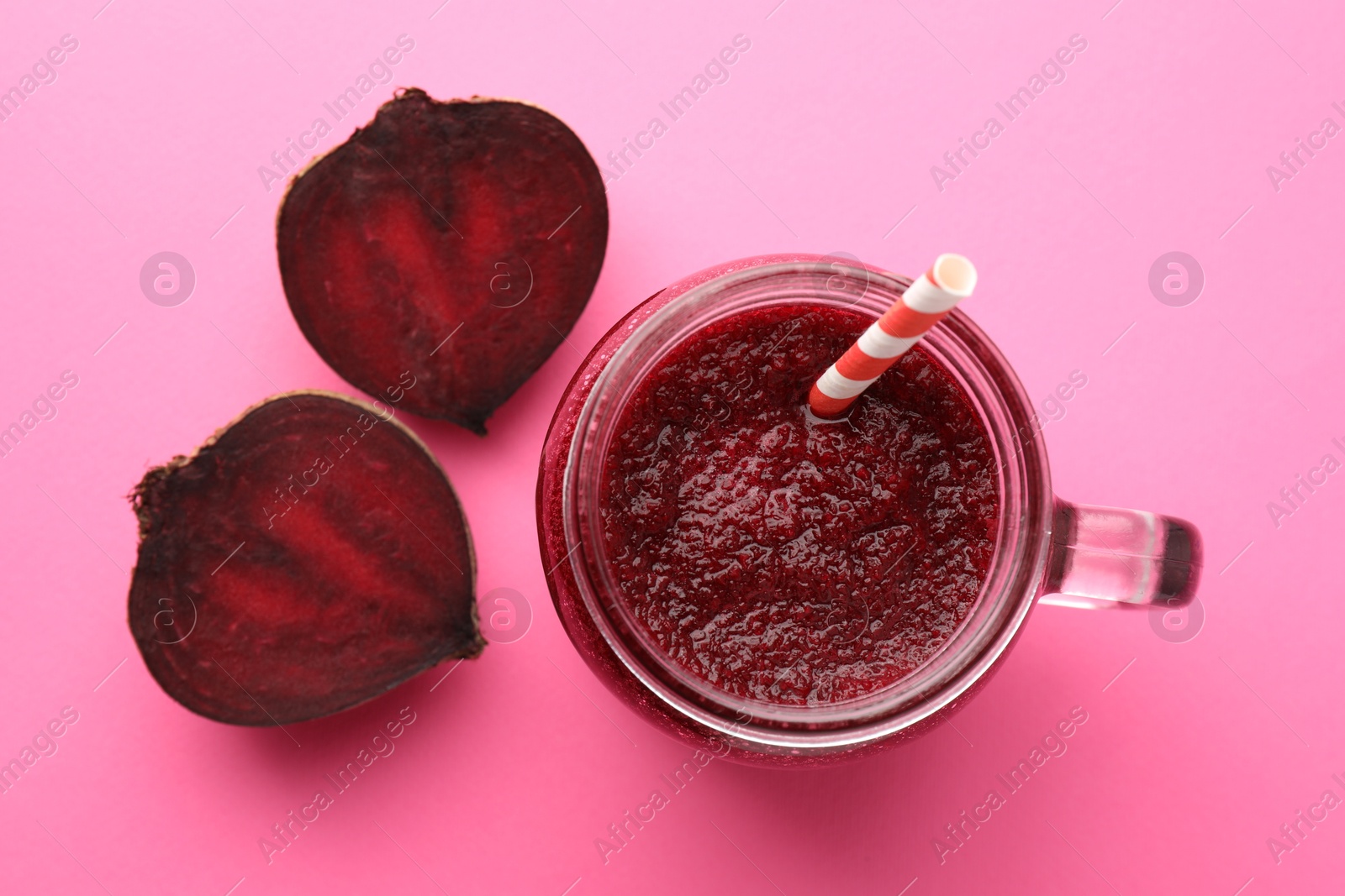 Photo of Fresh beetroot smoothie in mason jar and halves of vegetable on pink background, flat lay