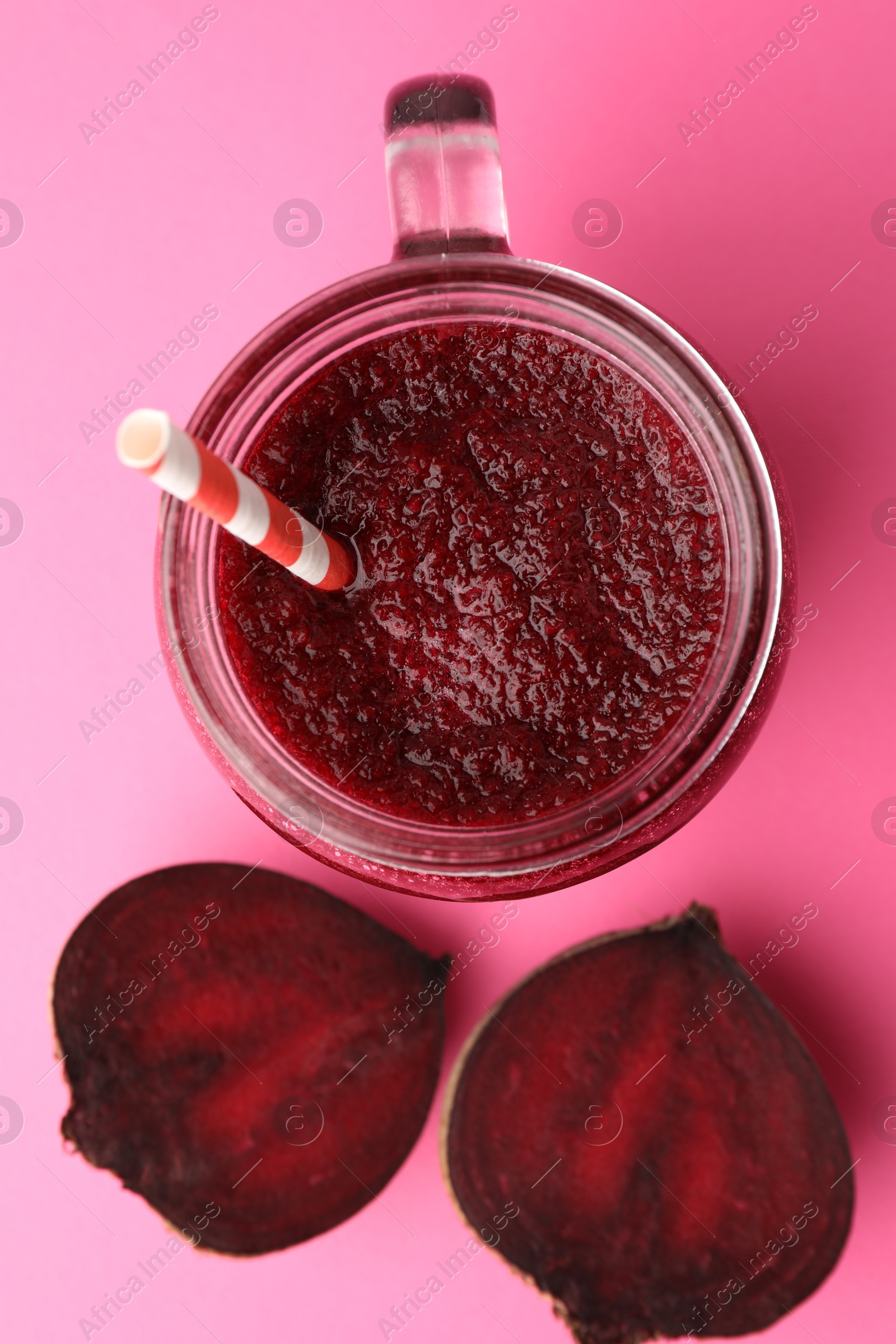 Photo of Fresh beetroot smoothie in mason jar and halves of vegetable on pink background, flat lay