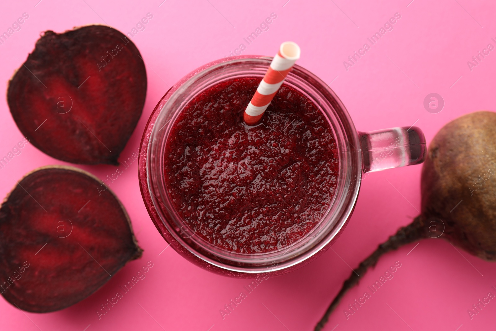 Photo of Fresh beetroot smoothie in mason jar and vegetables on pink background, flat lay