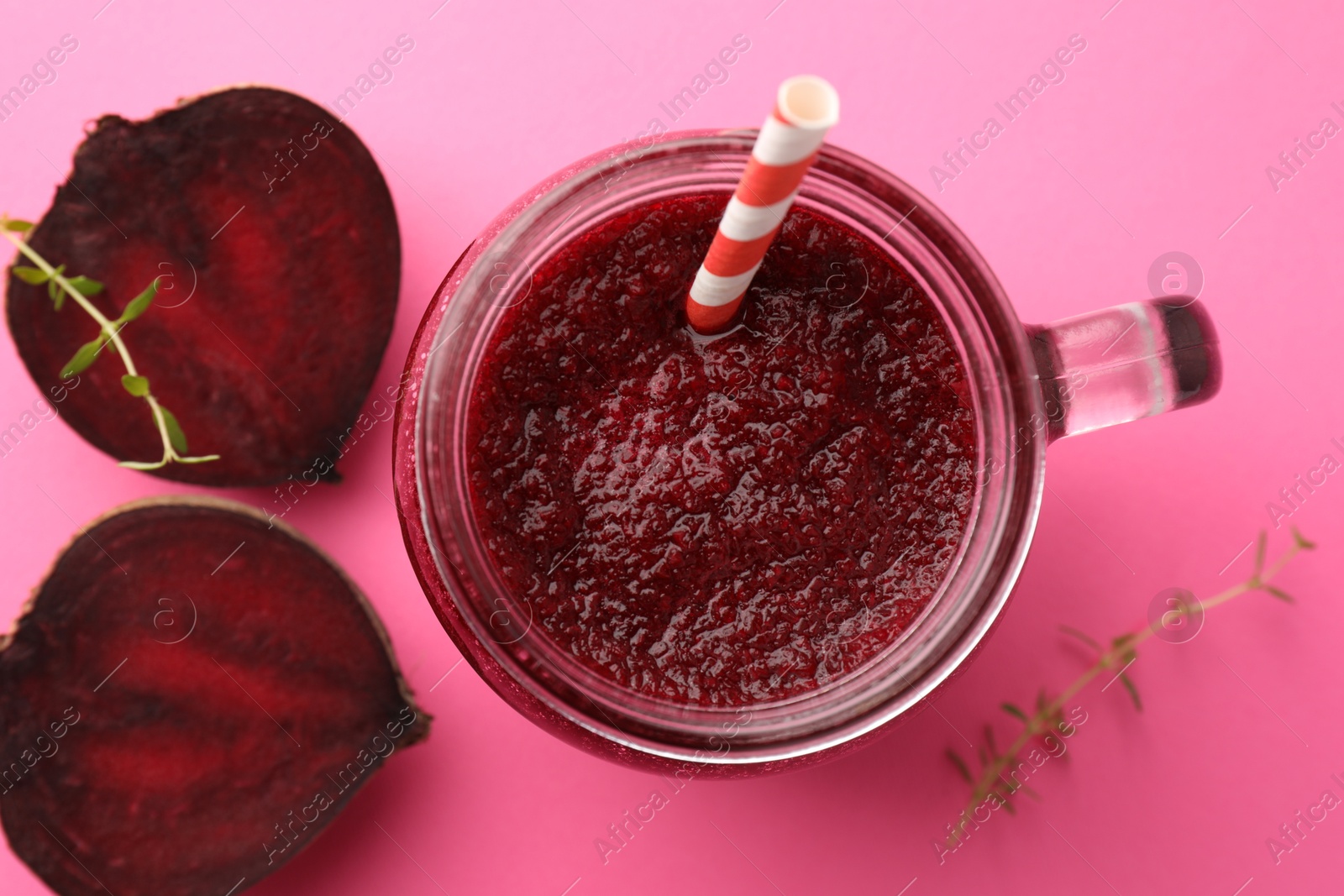 Photo of Fresh beetroot smoothie in mason jar and vegetables on pink background, flat lay