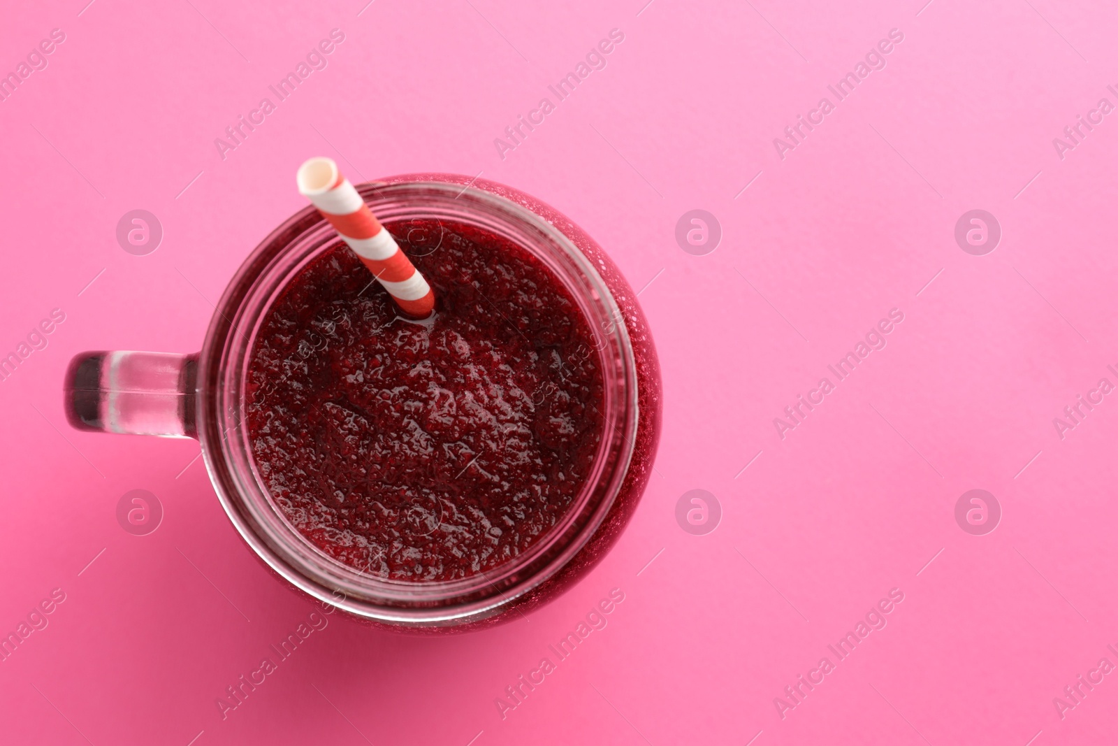 Photo of Fresh beetroot smoothie in mason jar on pink background, top view. Space for text