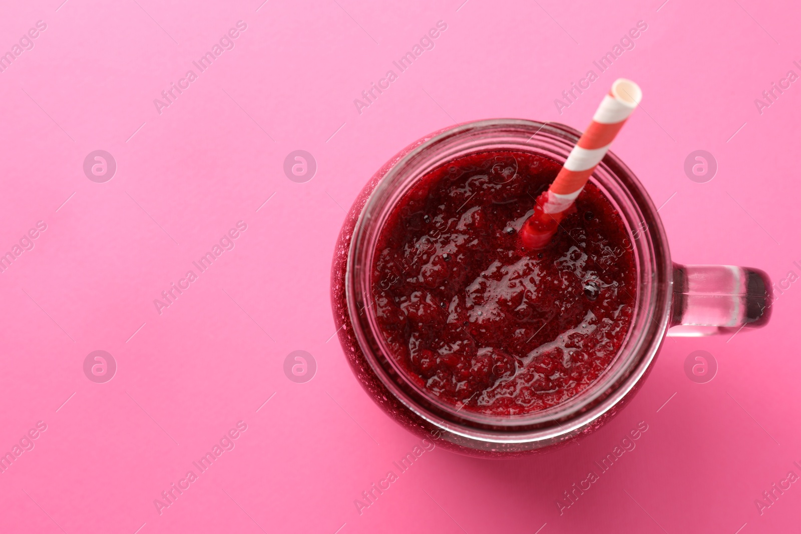 Photo of Fresh beetroot smoothie in mason jar on pink background, top view. Space for text