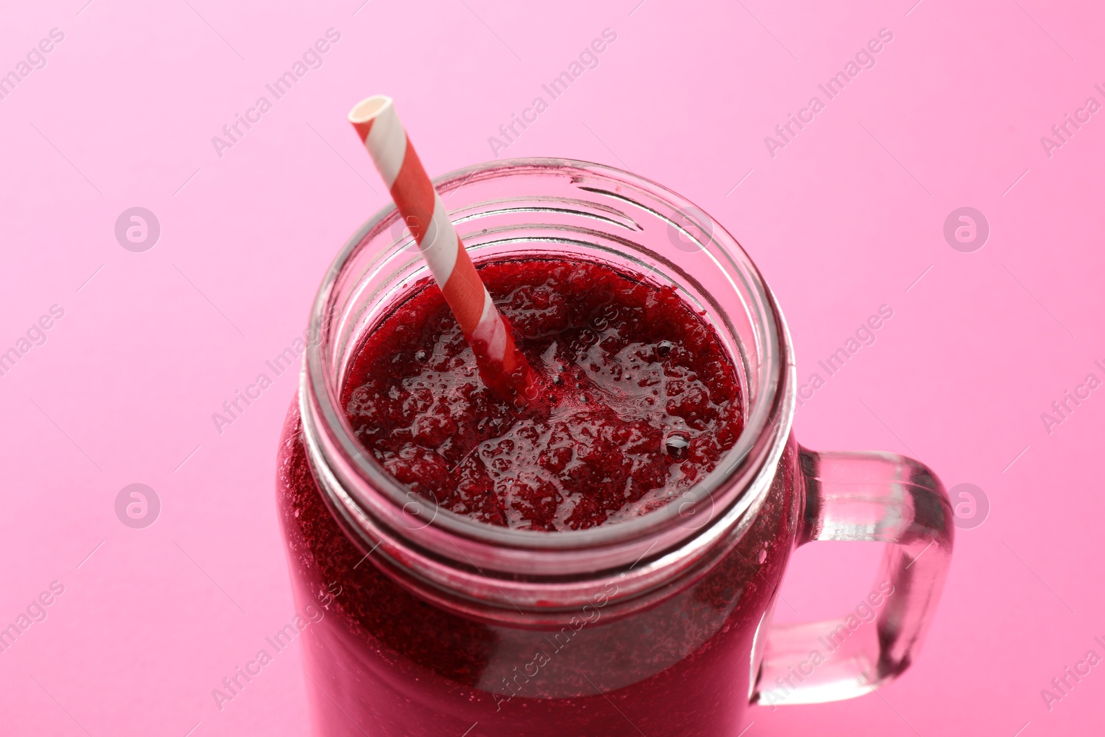 Photo of Fresh beetroot smoothie in mason jar on pink background, closeup