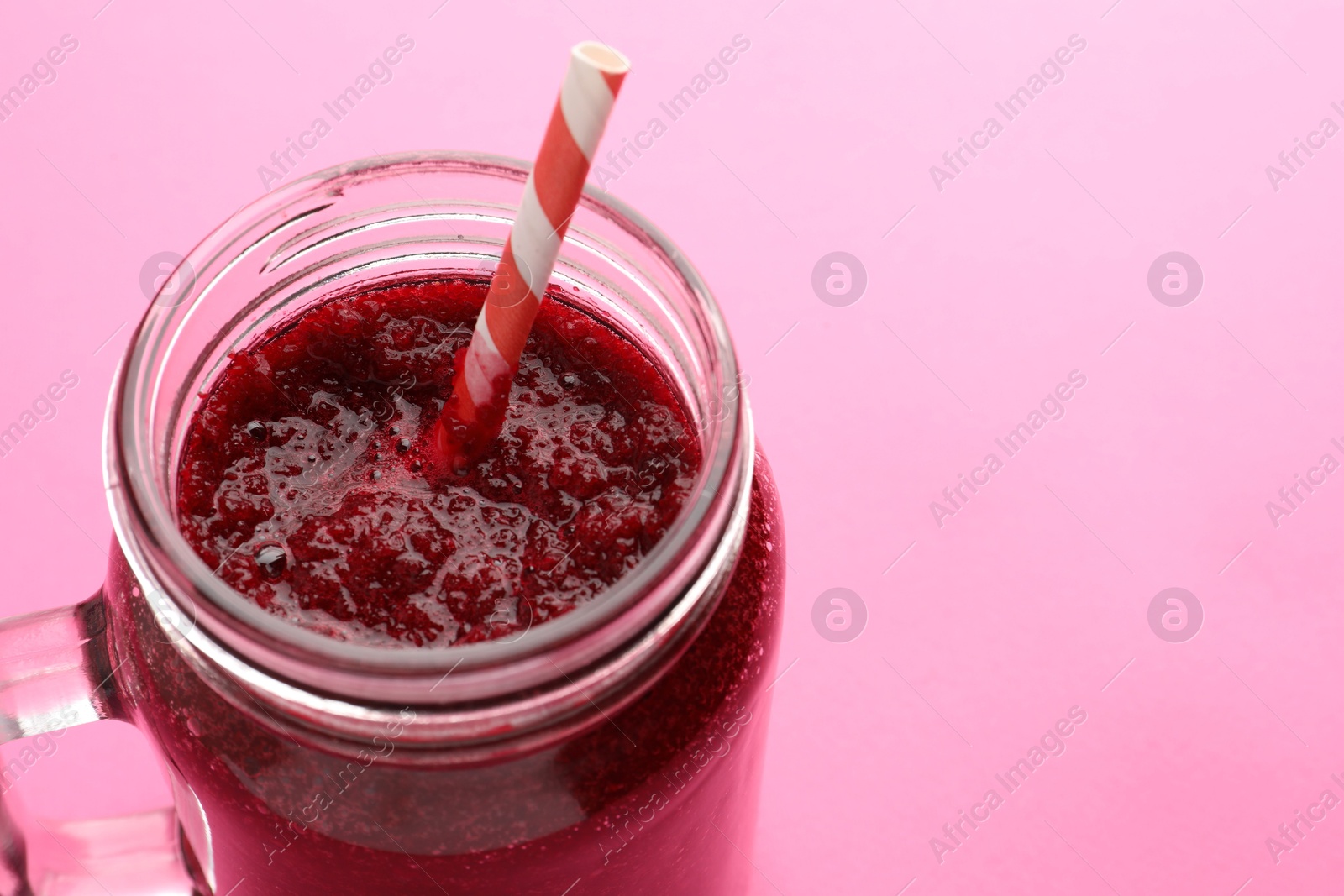 Photo of Fresh beetroot smoothie in mason jar on pink background, closeup. Space for text