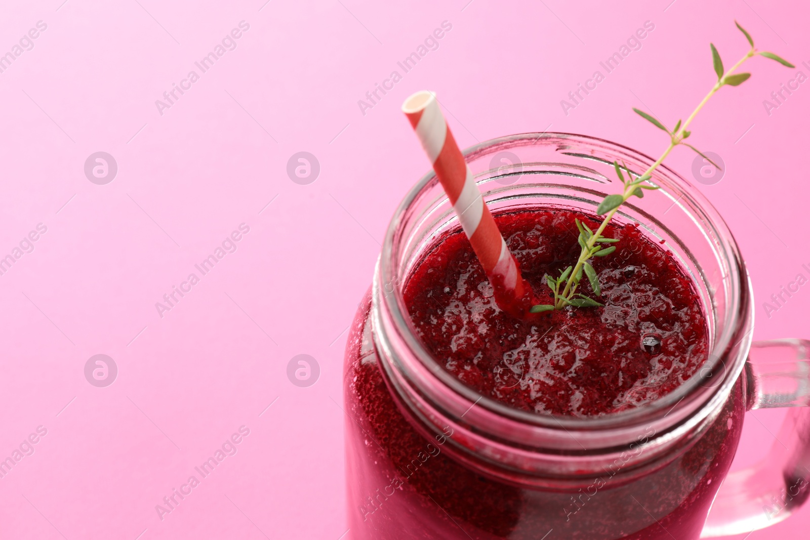 Photo of Fresh beetroot smoothie with thyme in mason jar on pink background, closeup. Space for text