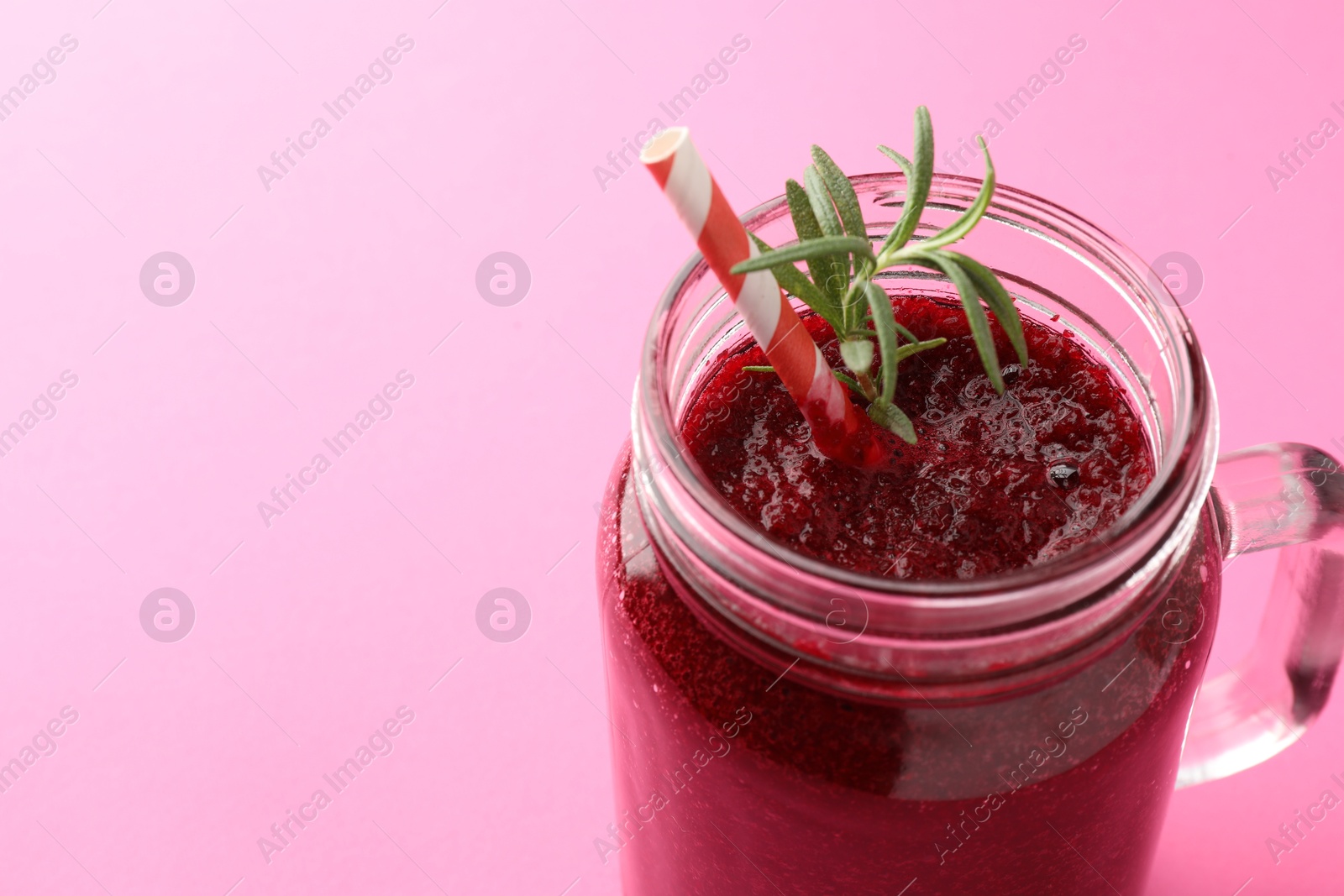 Photo of Fresh beetroot smoothie with rosemary in mason jar on pink background, closeup. Space for text