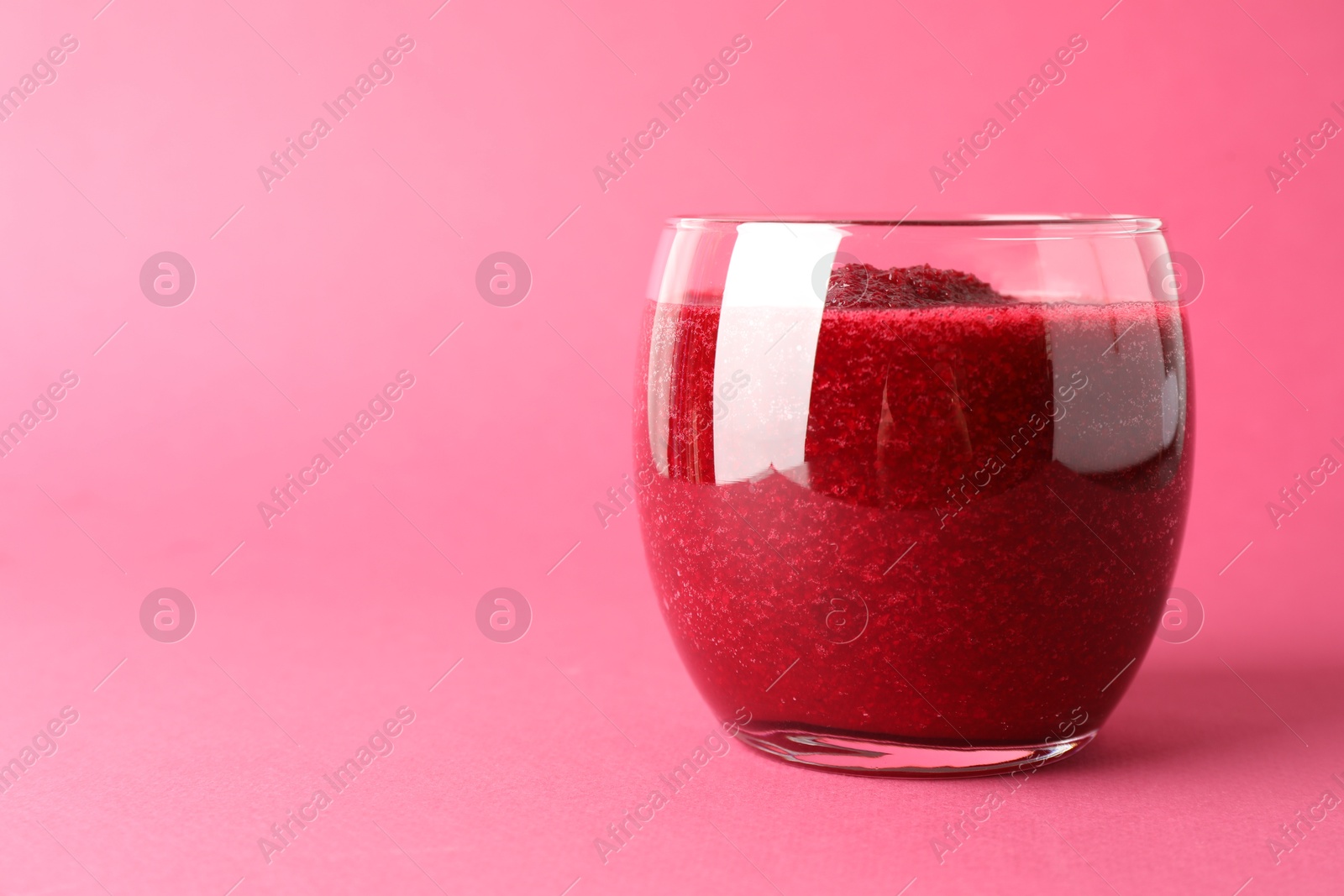 Photo of Fresh beetroot smoothie in glass on pink background, closeup. Space for text