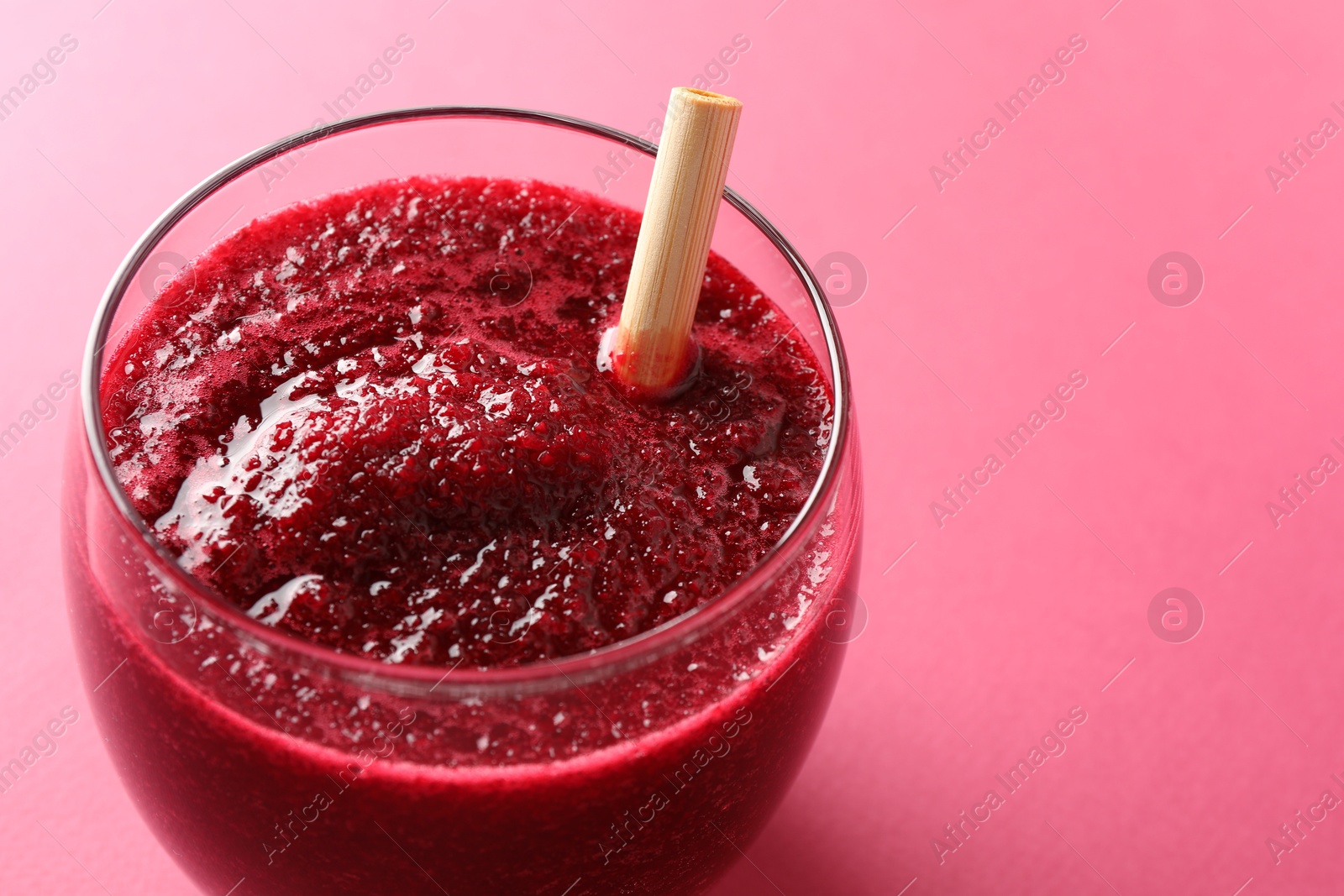 Photo of Fresh beetroot smoothie in glass on pink background, closeup. Space for text