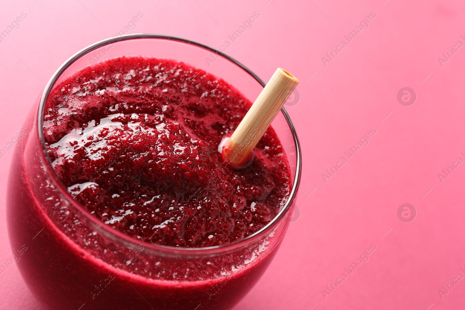 Photo of Fresh beetroot smoothie in glass on pink background, closeup. Space for text