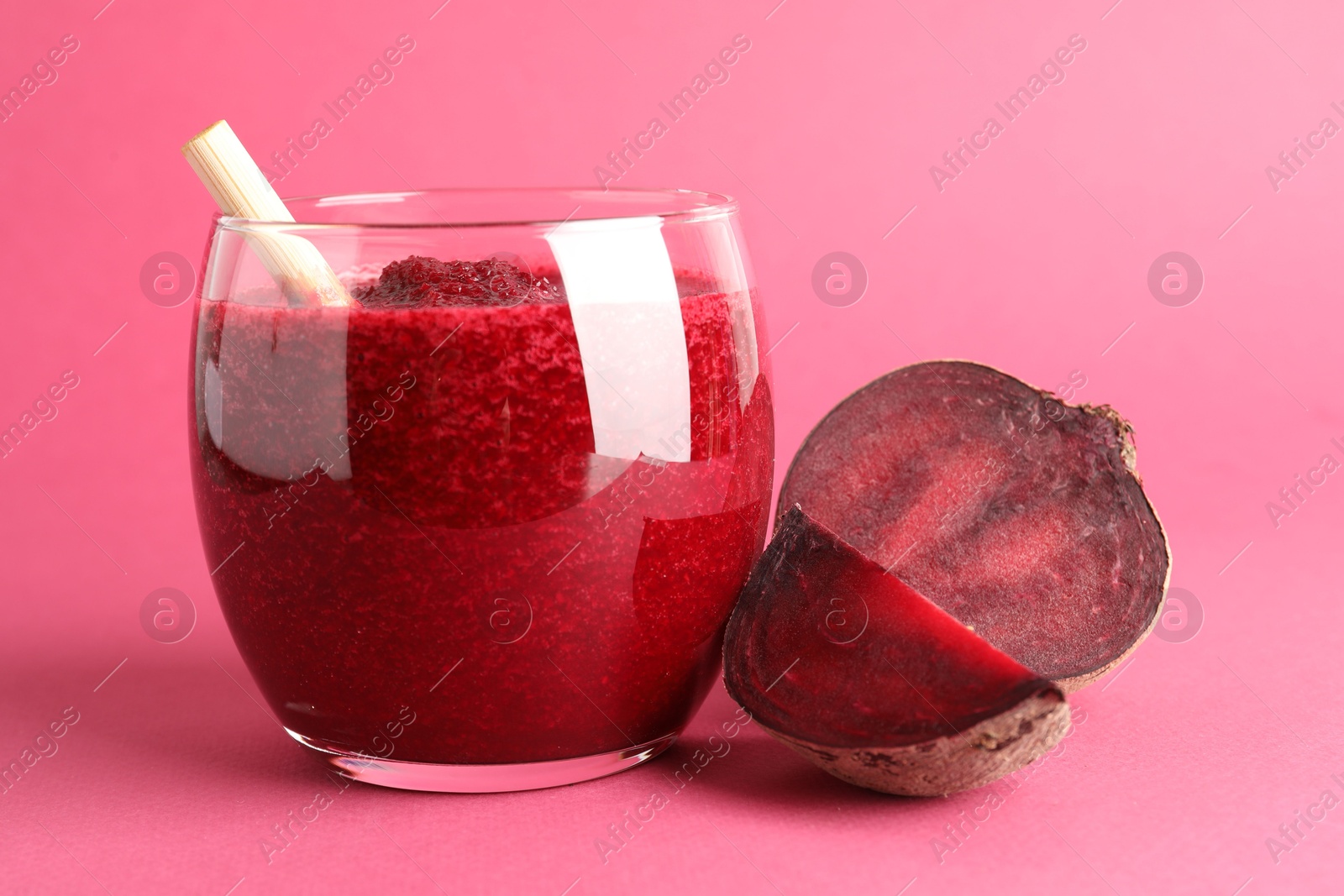 Photo of Fresh beetroot smoothie in glass and cut vegetable on pink background, closeup