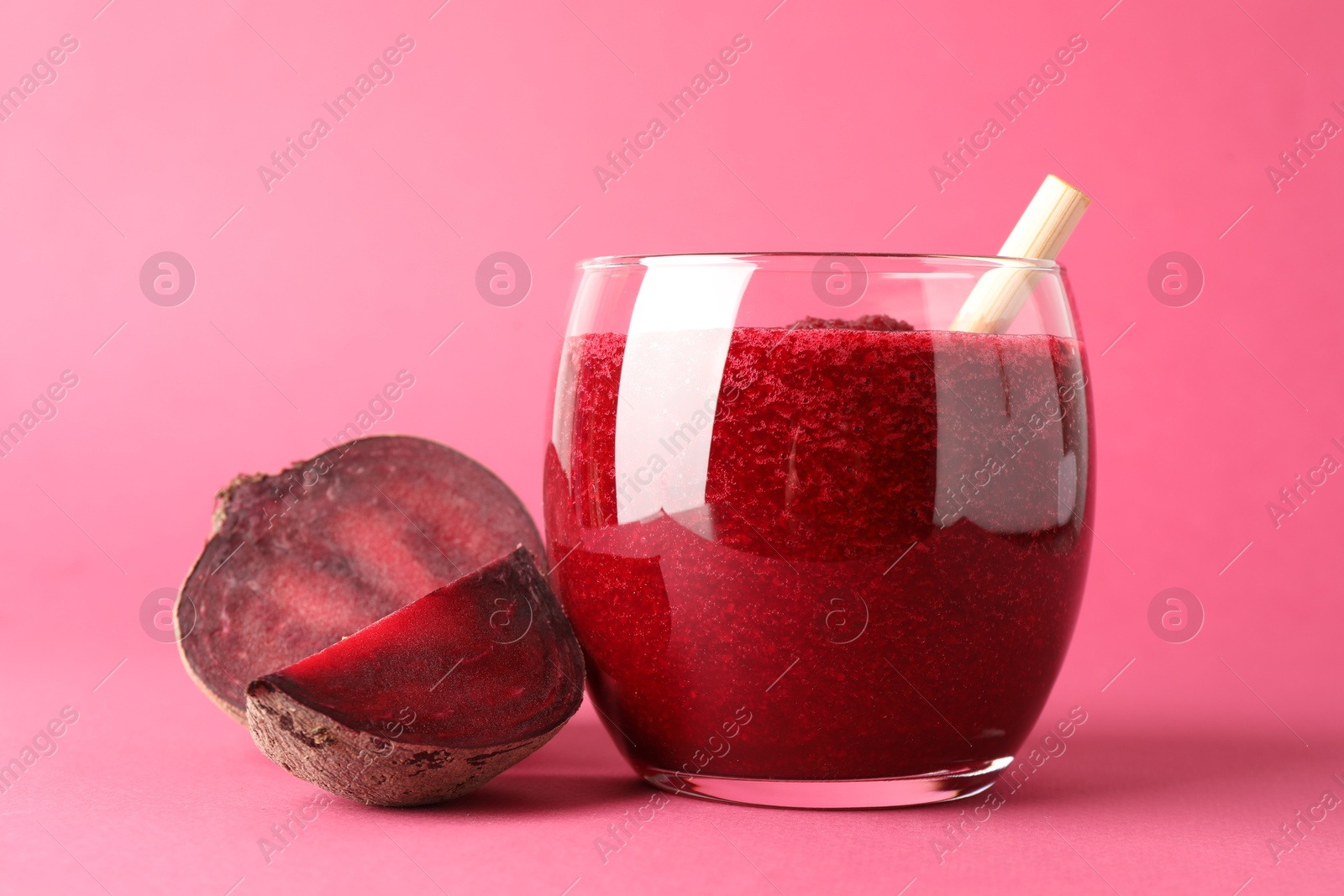 Photo of Fresh beetroot smoothie in glass and cut vegetable on pink background, closeup