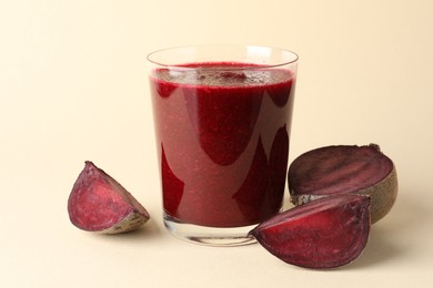 Photo of Fresh beetroot smoothie in glass and cut vegetable on beige background, closeup