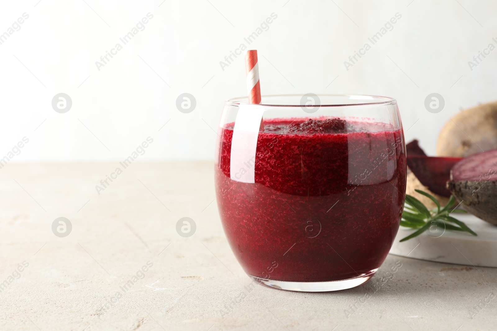 Photo of Fresh beetroot smoothie in glass on grey textured table, closeup. Space for text