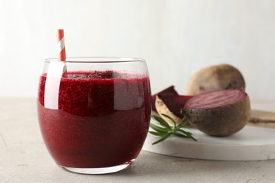 Photo of Fresh beetroot smoothie in glass on grey textured table, closeup