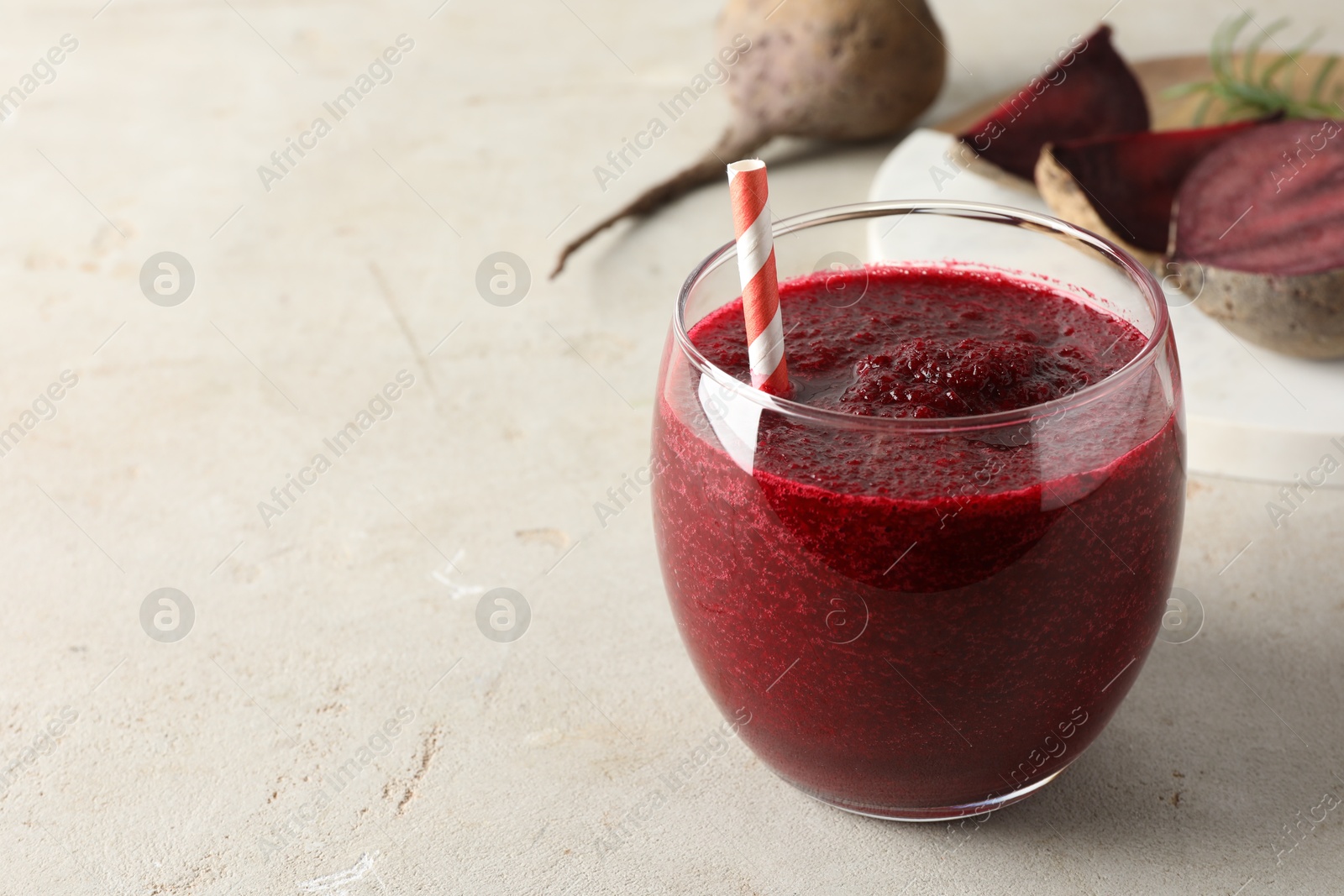 Photo of Fresh beetroot smoothie in glass on grey textured table, closeup. Space for text