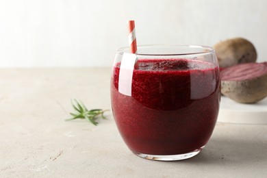 Photo of Fresh beetroot smoothie in glass on grey textured table, closeup. Space for text