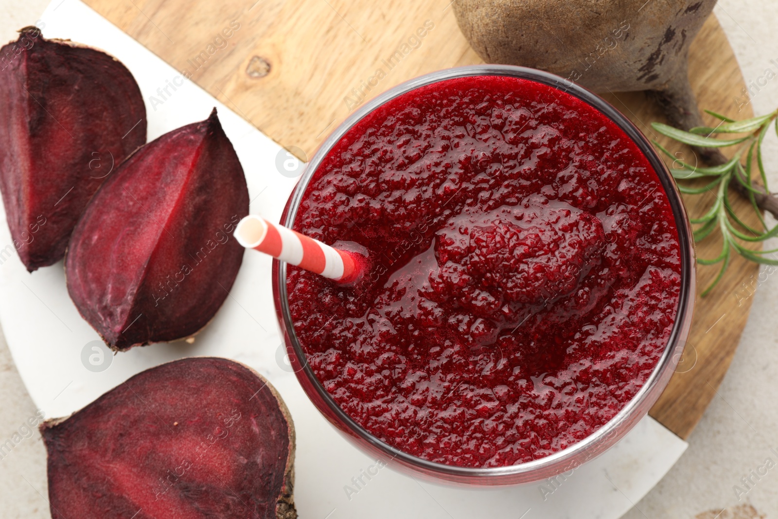 Photo of Fresh beetroot smoothie in glass and cut vegetable on light table, flat lay