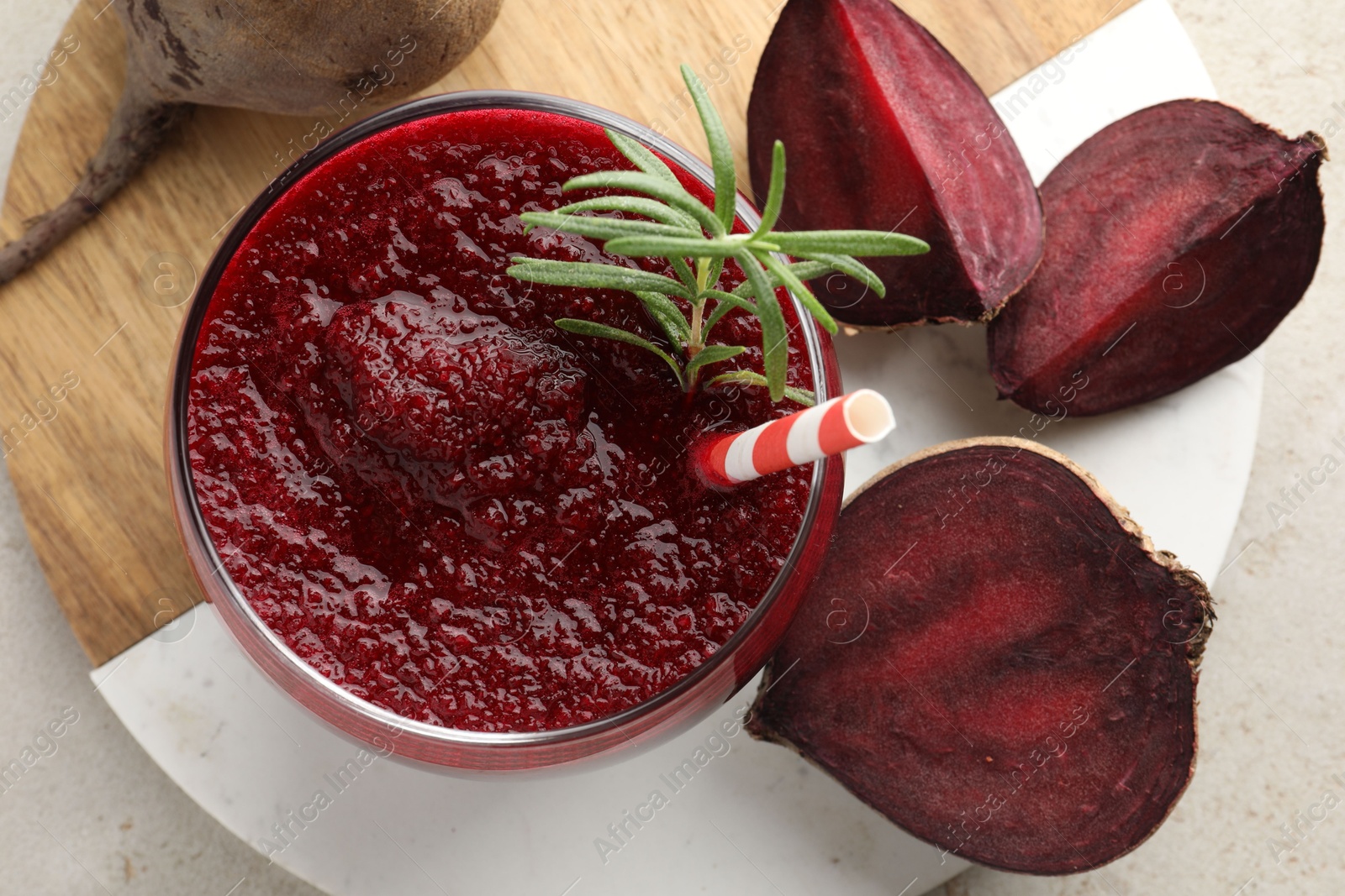 Photo of Fresh beetroot smoothie with rosemary in glass and cut vegetable on light table, flat lay