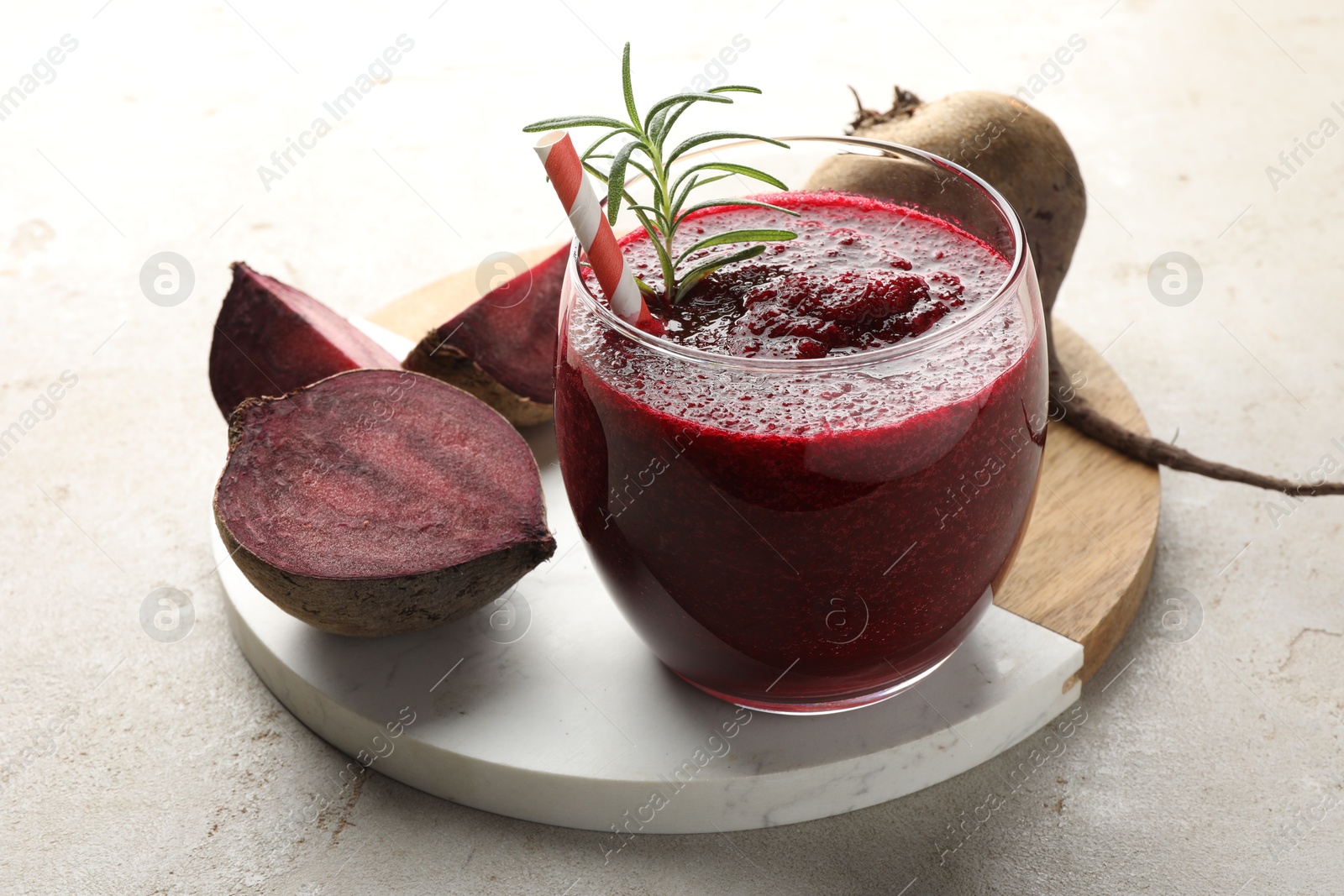 Photo of Fresh beetroot smoothie with rosemary in glass and cut vegetable on light textured table, closeup