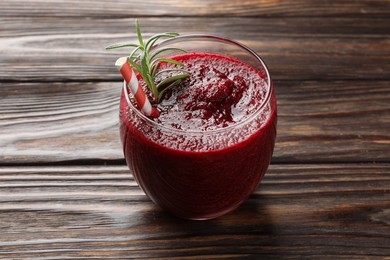 Photo of Fresh beetroot smoothie with rosemary in glass on wooden table, closeup