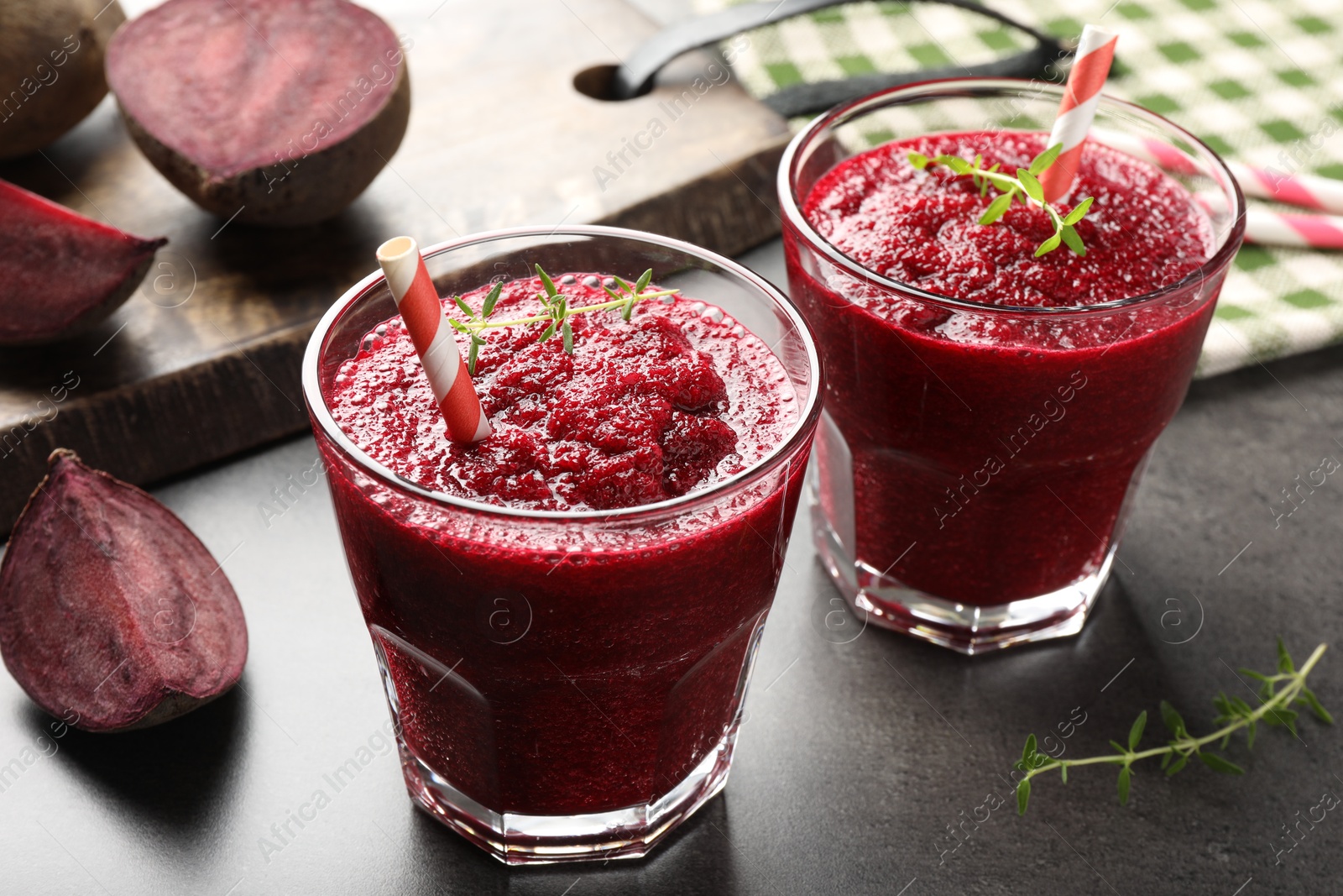 Photo of Fresh beetroot smoothie in glasses and cut vegetables on grey textured table, closeup