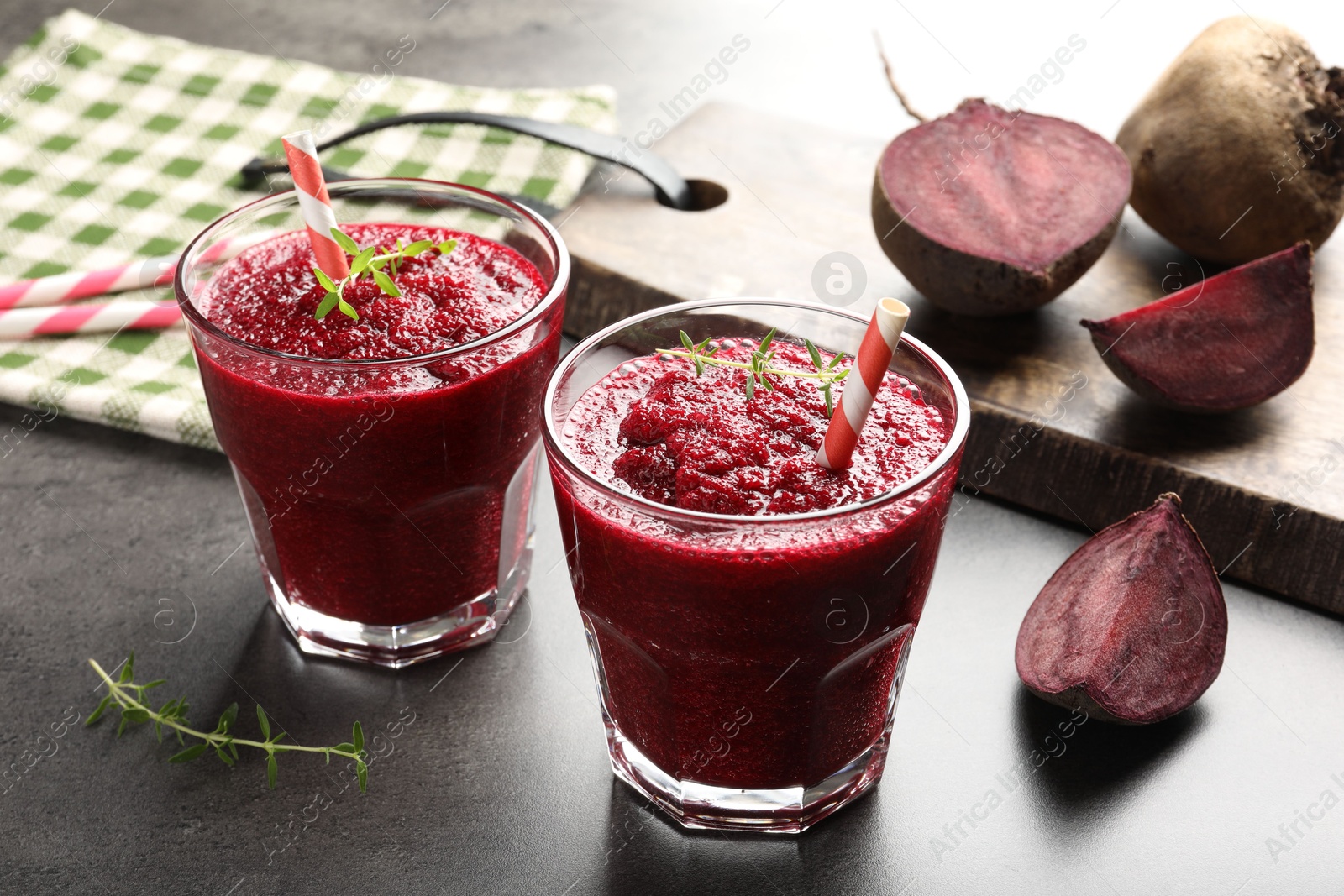 Photo of Fresh beetroot smoothie in glasses and cut vegetables on grey textured table, closeup