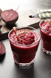 Photo of Fresh beetroot smoothie in glasses and cut vegetables on grey textured table, closeup