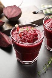 Photo of Fresh beetroot smoothie in glass and cut vegetables on grey textured table, closeup