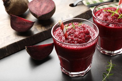 Photo of Fresh beetroot smoothie in glasses and cut vegetables on grey textured table, closeup