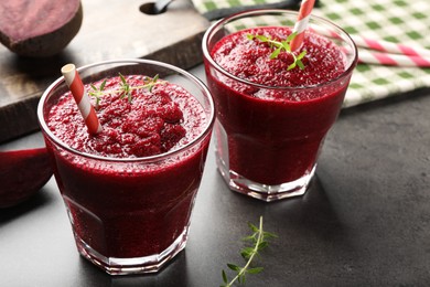 Photo of Fresh beetroot smoothie in glasses and cut vegetables on grey textured table, closeup