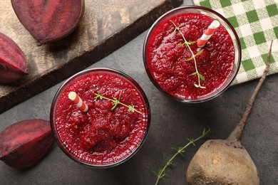 Photo of Fresh beetroot smoothie in glasses and cut vegetables on grey textured table, flat lay