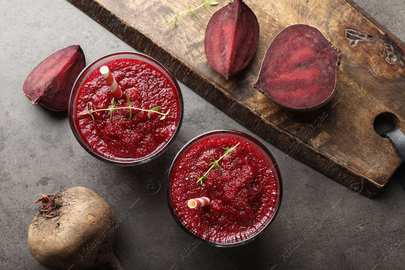 Photo of Fresh beetroot smoothie in glasses and cut vegetables on grey textured table, flat lay