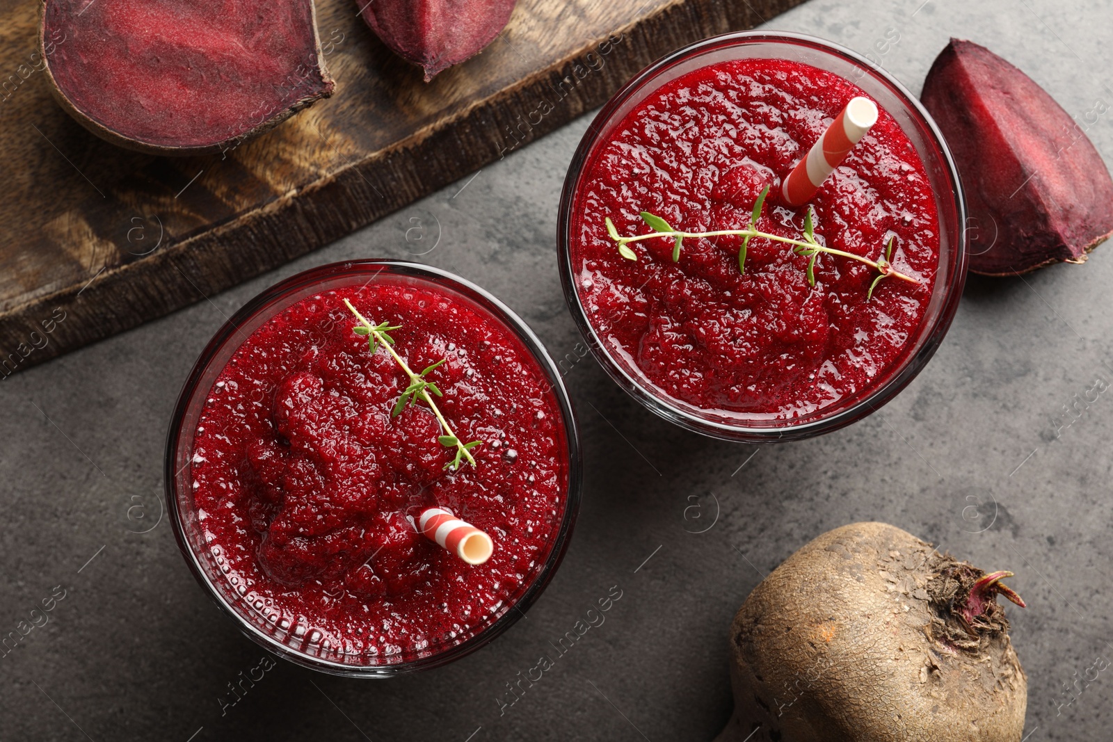 Photo of Fresh beetroot smoothie in glasses and cut vegetables on grey textured table, flat lay