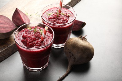 Photo of Fresh beetroot smoothie in glasses and vegetables on grey textured table, closeup