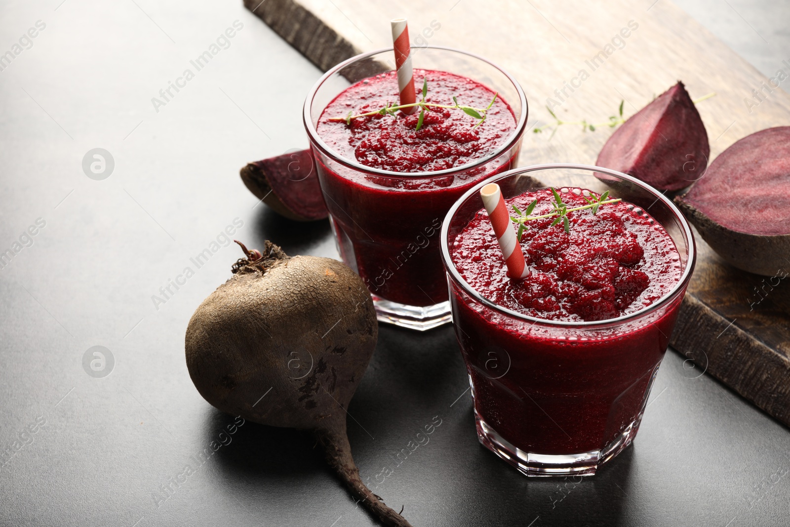 Photo of Fresh beetroot smoothie in glasses and vegetables on grey textured table, closeup