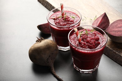 Photo of Fresh beetroot smoothie in glasses and vegetables on grey textured table, closeup