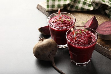 Photo of Fresh beetroot smoothie in glasses and vegetables on grey textured table, closeup. Space for text