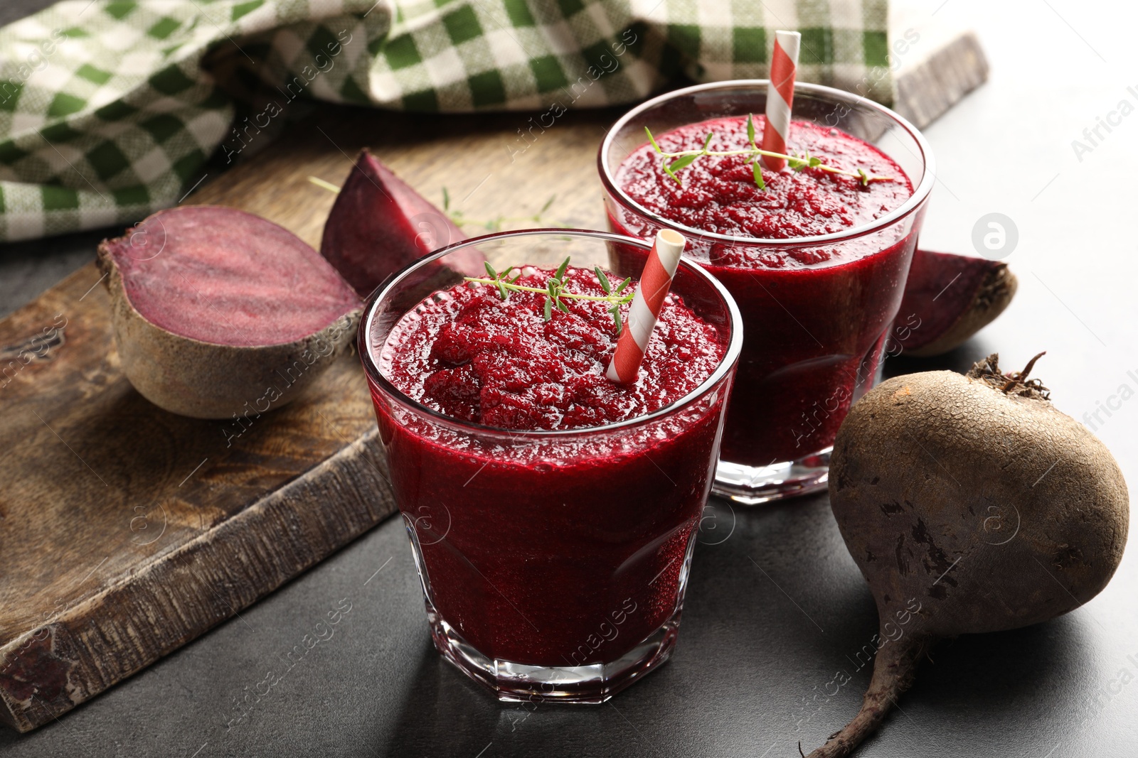 Photo of Fresh beetroot smoothie in glasses and vegetables on grey textured table, closeup