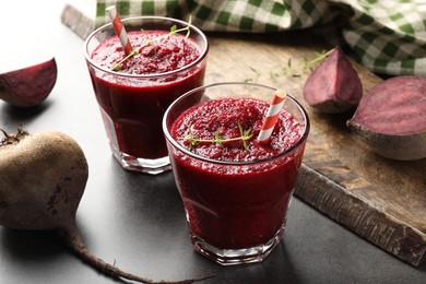 Photo of Fresh beetroot smoothie in glasses and vegetables on grey textured table, closeup