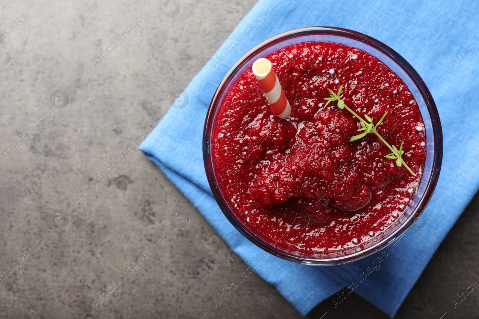 Photo of Fresh beetroot smoothie with thyme in glass on grey textured table, top view. Space for text