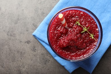 Photo of Fresh beetroot smoothie with thyme in glass on grey textured table, top view. Space for text