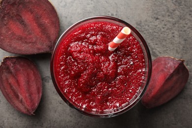 Photo of Fresh beetroot smoothie in glass and cut vegetable on grey textured table, flat lay